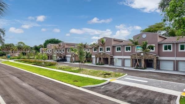 1563 NW 94th Way Unit 09, Coral Springs, FL 33071 - view of front facade with a residential view, a garage, stucco siding, and driveway
