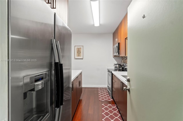 1700 NE 105th St Unit 312, Miami Shores, FL 33138 - kitchen featuring stainless steel appliances, light countertops, brown cabinetry, and dark wood finished floors