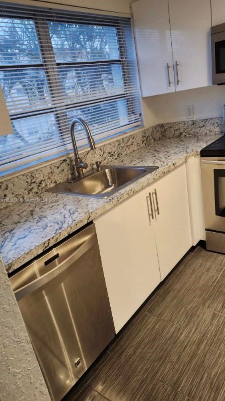 2501 NW 41st Ave Unit 201, Lauderhill, FL 33313 - kitchen featuring stainless steel appliances, white cabinets, and light stone countertops