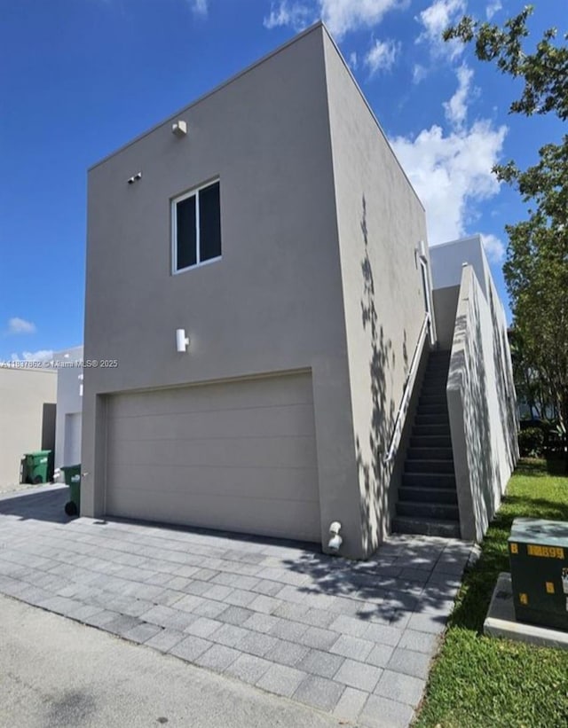 10440 NW 67th St Unit 10440, Doral, FL 33178 - view of home's exterior featuring stucco siding, an attached garage, stairs, and decorative driveway