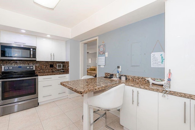 2814 N 46th Ave Unit H277, Hollywood, FL 33021 - kitchen featuring appliances with stainless steel finishes, white cabinetry, decorative backsplash, light tile patterned flooring, and a peninsula