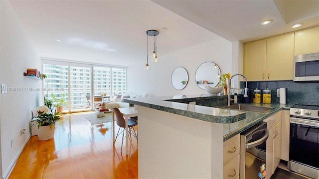 5600 Collins Ave Unit 10A, Miami Beach, FL 33140 - kitchen featuring appliances with stainless steel finishes, tasteful backsplash, a peninsula, light wood-type flooring, and cream cabinets