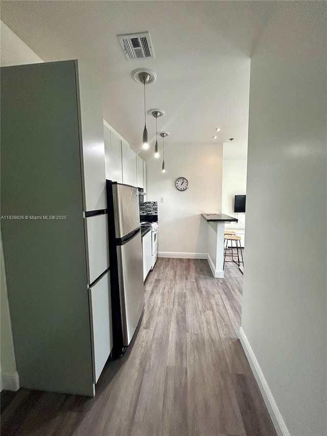 1244 Pennsylvania Ave Unit 305, Miami Beach, FL 33139 - kitchen featuring freestanding refrigerator, dark wood finished floors, white cabinetry, a breakfast bar area, and white gas range