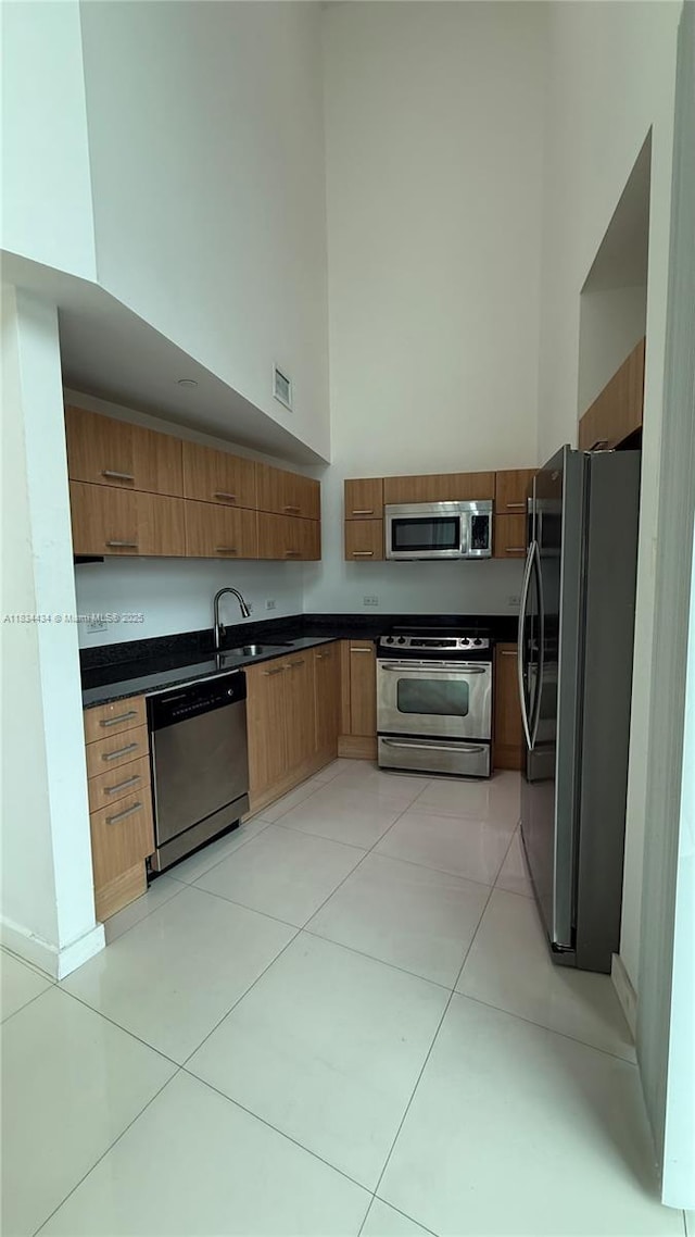 350 S Miami Ave Unit 312, Miami, FL 33130 - kitchen featuring appliances with stainless steel finishes, dark countertops, a high ceiling, brown cabinets, and modern cabinets
