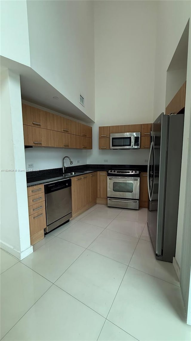 350 S Miami Ave Unit 312, Miami, FL 33130 - kitchen featuring appliances with stainless steel finishes, dark countertops, a high ceiling, brown cabinetry, and modern cabinets