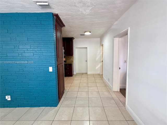 2406 N 28th Ave, Hollywood, FL 33020 - corridor with light tile patterned floors, a textured ceiling, and brick wall