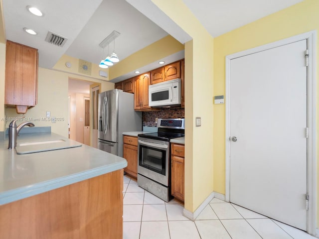 1440 Egret Rd, Homestead, FL 33035 - kitchen featuring stainless steel appliances, tasteful backsplash, light tile patterned floors, light countertops, and brown cabinets
