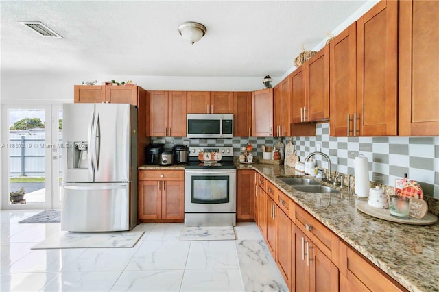 231 E 41st St, Hialeah, FL 33013 - kitchen with appliances with stainless steel finishes, light stone countertops, light marble finish flooring, brown cabinets, and a textured ceiling