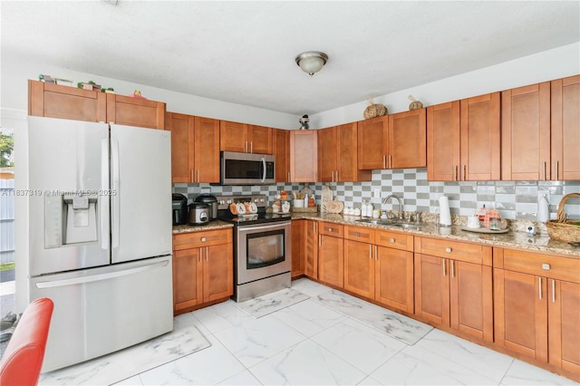 231 E 41st St, Hialeah, FL 33013 - kitchen with appliances with stainless steel finishes, light marble finish flooring, light stone counters, tasteful backsplash, and brown cabinets
