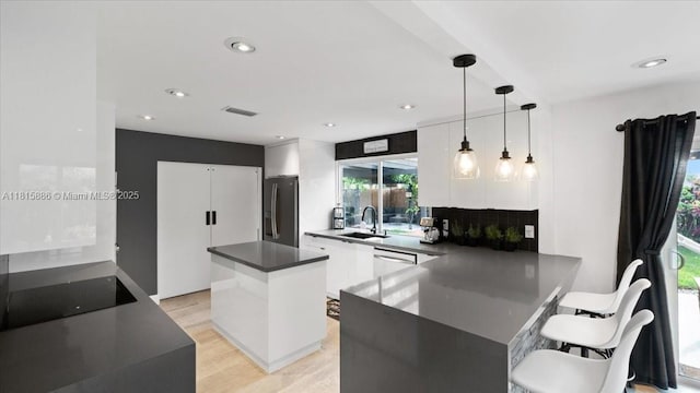 18701 Shauna Manor Dr, Boca Raton, FL 33496 - kitchen featuring stainless steel appliances, dark countertops, white cabinetry, light wood-style flooring, and modern cabinets