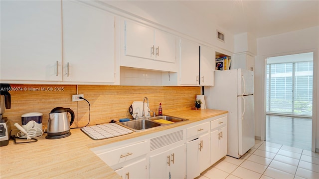10178 Collins Ave Unit 102, Bal Harbour, FL 33154 - kitchen featuring light countertops, freestanding refrigerator, white cabinetry, and backsplash
