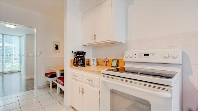 10178 Collins Ave Unit 102, Bal Harbour, FL 33154 - kitchen with electric stove, light tile patterned floors, light countertops, white cabinetry, and backsplash