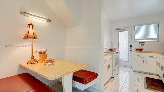 10178 Collins Ave Unit 102, Bal Harbour, FL 33154 - kitchen with electric range, white cabinets, light tile patterned floors, light countertops, and vaulted ceiling