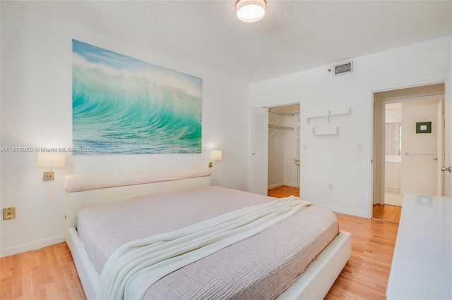 19701 E Country Club Dr Unit 5104, Aventura, FL 33180 - bedroom featuring light wood-type flooring, a textured ceiling, and a walk in closet
