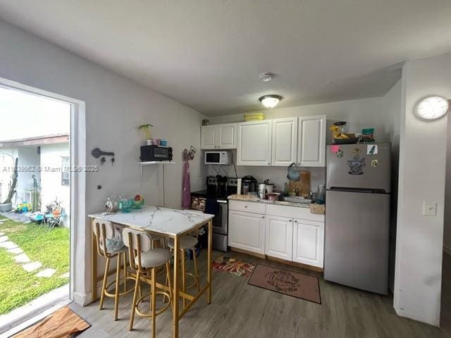 7230 NW 3rd St, Miami, FL 33126 - kitchen featuring appliances with stainless steel finishes, light wood finished floors, white cabinetry, and light stone countertops