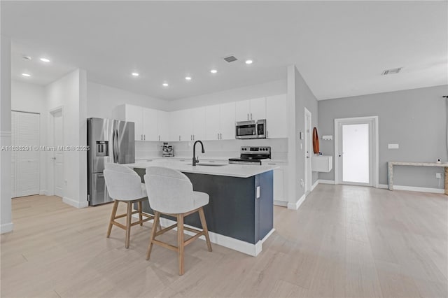 14864 SW 163rd Ter, Miami, FL 33187 - kitchen with appliances with stainless steel finishes, light countertops, a kitchen bar, a center island with sink, and light wood-style floors