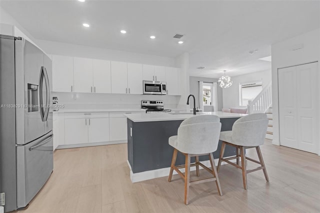 14864 SW 163rd Ter, Miami, FL 33187 - kitchen with appliances with stainless steel finishes, light wood finished floors, a kitchen bar, a kitchen island with sink, and recessed lighting