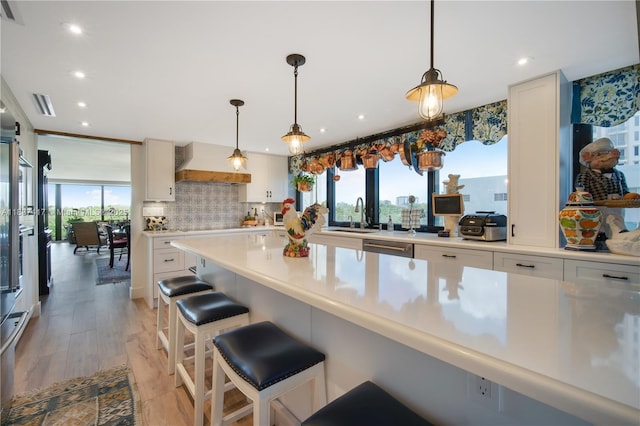 700 Coral Way Unit 4, Coral Gables, FL 33134 - kitchen with custom range hood, light countertops, recessed lighting, decorative backsplash, and a kitchen bar