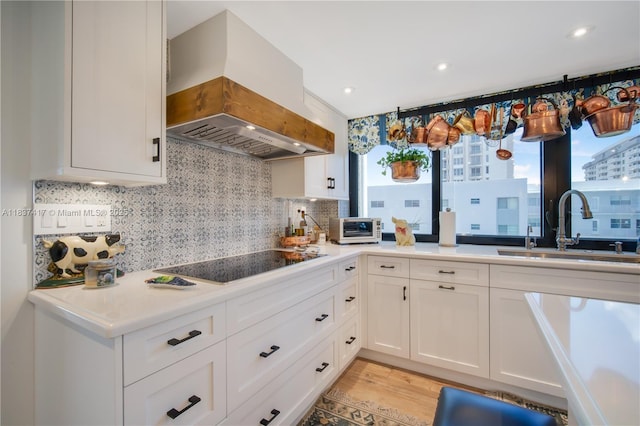 700 Coral Way Unit 4, Coral Gables, FL 33134 - kitchen with custom exhaust hood, black electric stovetop, tasteful backsplash, white cabinets, and light wood-type flooring
