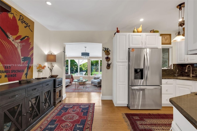1420 NE 15th Ave, Fort Lauderdale, FL 33304 - kitchen with stainless steel fridge with ice dispenser, white cabinets, light wood finished floors, backsplash, and recessed lighting