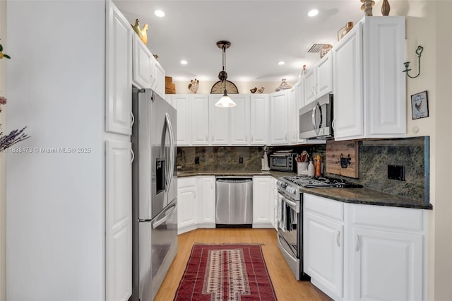 1420 NE 15th Ave, Fort Lauderdale, FL 33304 - kitchen featuring stainless steel appliances, light wood-style floors, white cabinets, backsplash, and pendant lighting