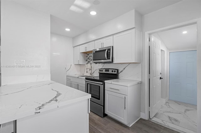 15900 NW 18th Ave, Miami Gardens, FL 33054 - kitchen featuring appliances with stainless steel finishes, light stone countertops, white cabinets, recessed lighting, and decorative backsplash