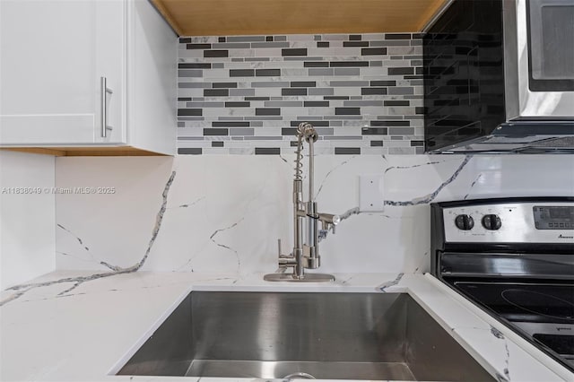 15900 NW 18th Ave, Miami Gardens, FL 33054 - kitchen view of tasteful backsplash, electric range, white cabinetry, light stone countertops, and stainless steel microwave