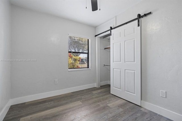 15900 NW 18th Ave, Miami Gardens, FL 33054 - unfurnished bedroom with a barn door, wood finished floors, and a ceiling fan