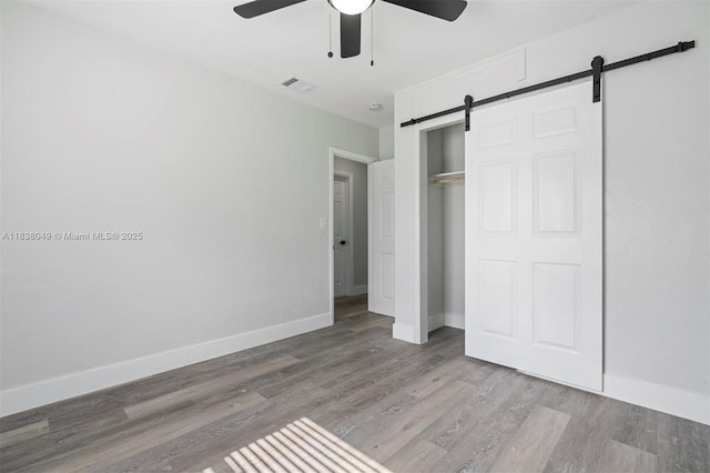 15900 NW 18th Ave, Miami Gardens, FL 33054 - unfurnished bedroom featuring a barn door, wood finished floors, a closet, and a ceiling fan