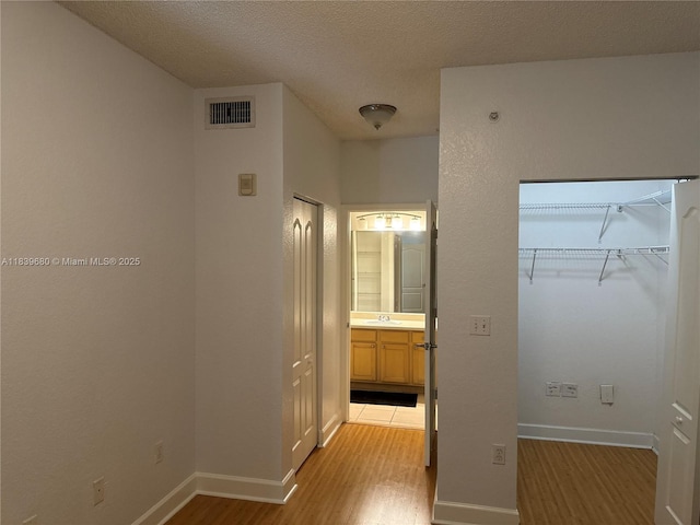 6001 SW 70th St Unit 304, South Miami, FL 33143 - unfurnished bedroom featuring light wood-style floors, a textured ceiling, and a walk in closet