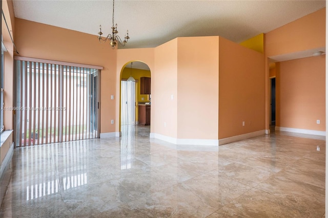 14677 SW 123rd Ave, Miami, FL 33186 - spare room featuring arched walkways, marble tiled floors, a textured ceiling, and a chandelier
