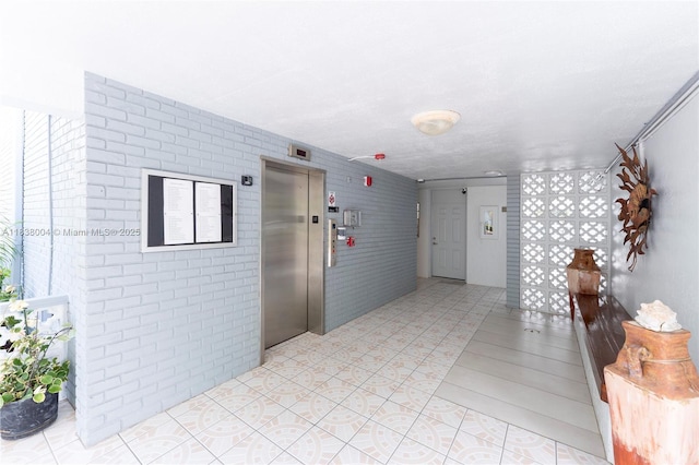 3551 NE 169th St Unit 411, North Miami Beach, FL 33160 - corridor with elevator, brick wall, and light tile patterned floors