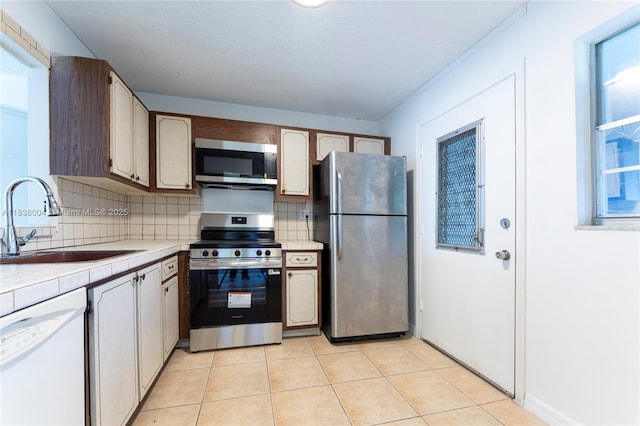 3551 NE 169th St Unit 411, North Miami Beach, FL 33160 - kitchen with stainless steel appliances, tasteful backsplash, tile counters, and light tile patterned floors