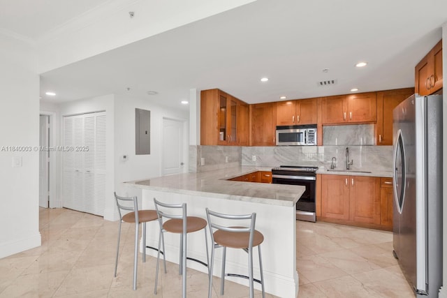 20 Calabria Ave Unit 505, Coral Gables, FL 33134 - kitchen with appliances with stainless steel finishes, a peninsula, electric panel, brown cabinets, and backsplash