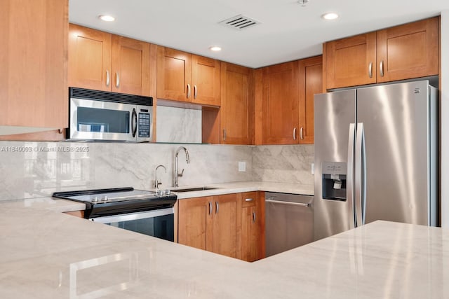 20 Calabria Ave Unit 505, Coral Gables, FL 33134 - kitchen featuring appliances with stainless steel finishes, decorative backsplash, brown cabinets, recessed lighting, and light stone counters