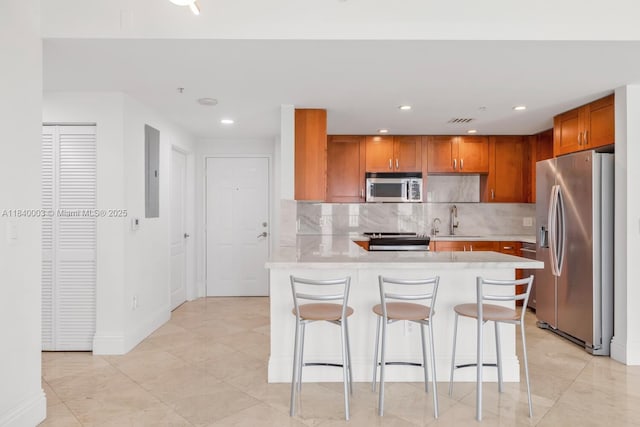 20 Calabria Ave Unit 505, Coral Gables, FL 33134 - kitchen featuring appliances with stainless steel finishes, a peninsula, light countertops, backsplash, and brown cabinetry