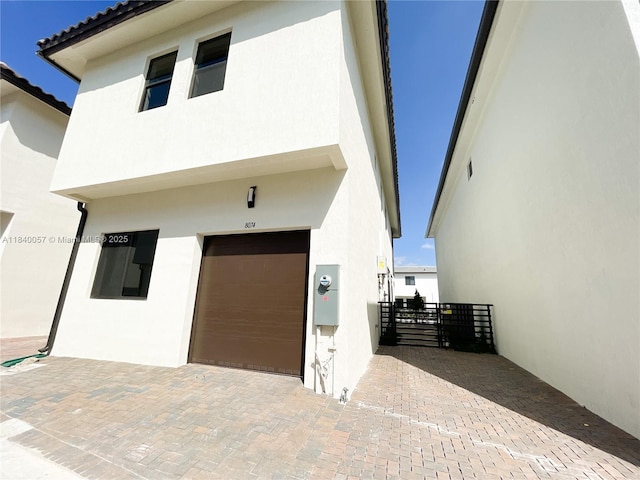 8074 NW 43rd St, Doral, FL 33166 - view of front of home with stucco siding, an attached garage, decorative driveway, and a gate
