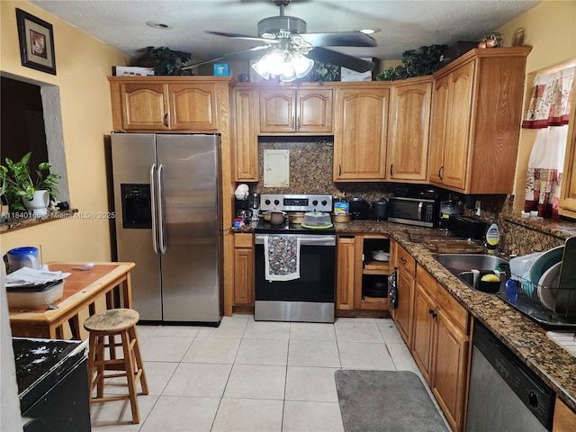 850 NE 172nd Ter, North Miami Beach, FL 33162 - kitchen featuring appliances with stainless steel finishes, ceiling fan, decorative backsplash, light tile patterned floors, and brown cabinetry
