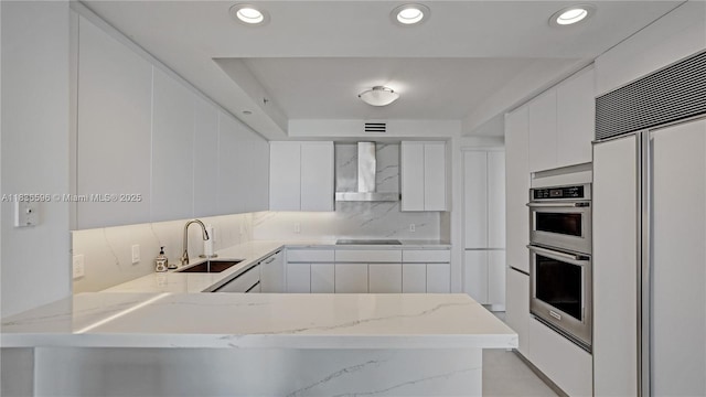 20201 E Country Club Dr Unit 1202, Aventura, FL 33180 - kitchen featuring wall chimney range hood, paneled refrigerator, modern cabinets, a peninsula, and white cabinets