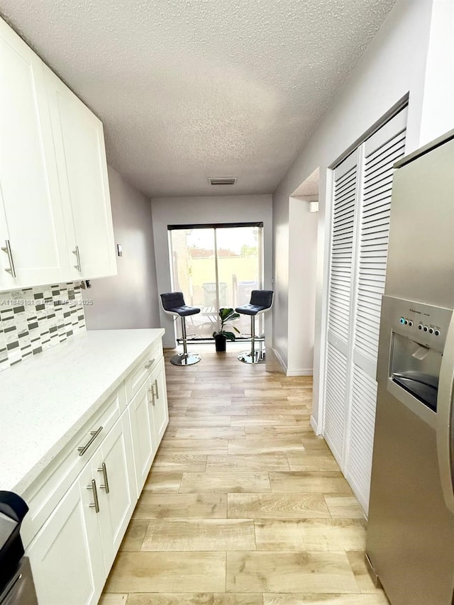 6169 NW 170th Ter, Hialeah, FL 33015 - kitchen featuring light wood-type flooring, a textured ceiling, white cabinets, decorative backsplash, and stainless steel built in refrigerator