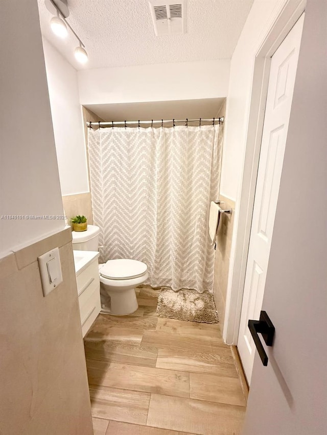 6169 NW 170th Ter, Hialeah, FL 33015 - full bath featuring wood finished floors, a textured ceiling, vanity, wainscoting, and a shower with shower curtain