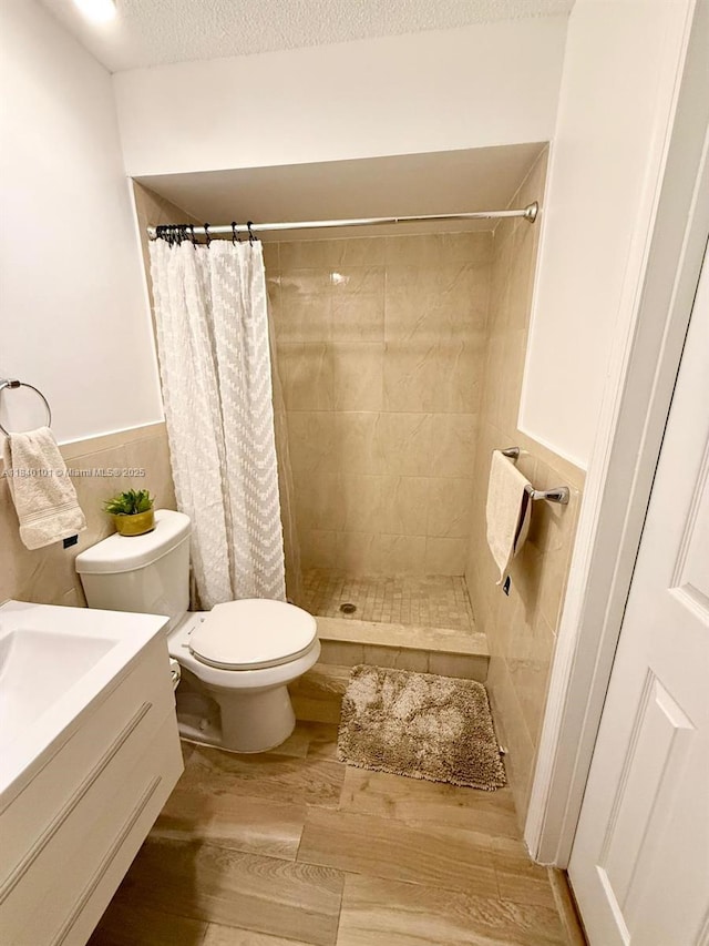 6169 NW 170th Ter, Hialeah, FL 33015 - bathroom with wood finished floors, a tile shower, vanity, a textured ceiling, and a wainscoted wall