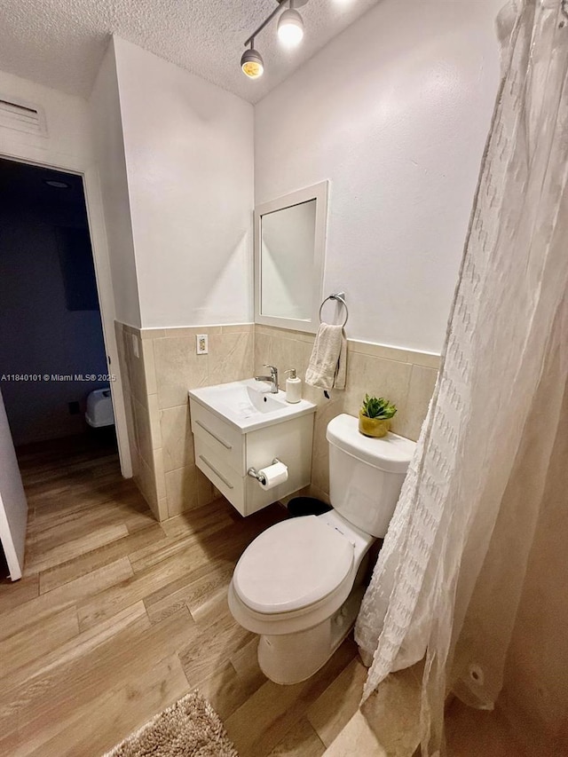 6169 NW 170th Ter, Hialeah, FL 33015 - full bath featuring tile walls, a textured ceiling, wainscoting, vanity, and wood finished floors