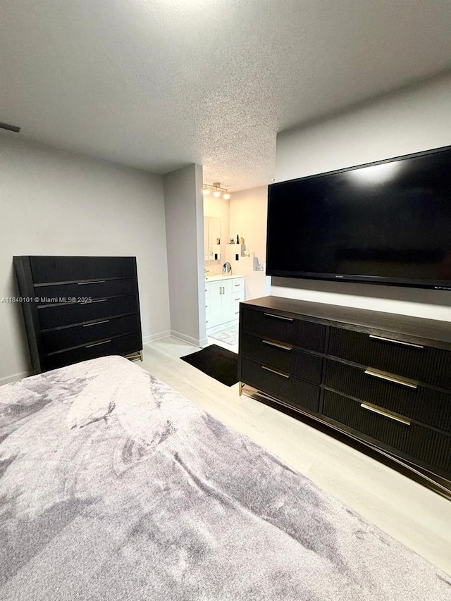 6169 NW 170th Ter, Hialeah, FL 33015 - bedroom featuring a textured ceiling, connected bathroom, and wood finished floors