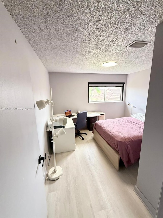 6169 NW 170th Ter, Hialeah, FL 33015 - bedroom with light wood finished floors, a desk, and a textured ceiling