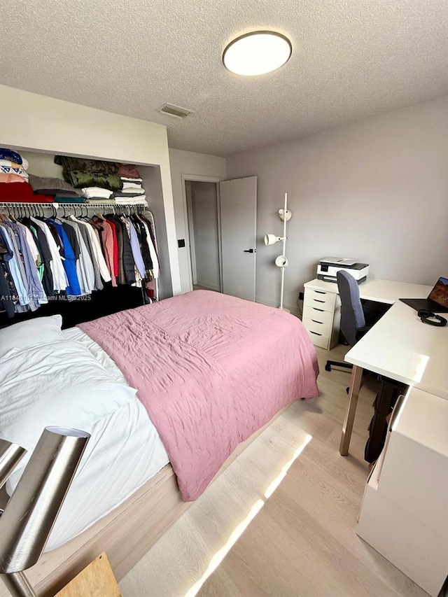 6169 NW 170th Ter, Hialeah, FL 33015 - bedroom with light wood finished floors, a textured ceiling, a closet, and a desk