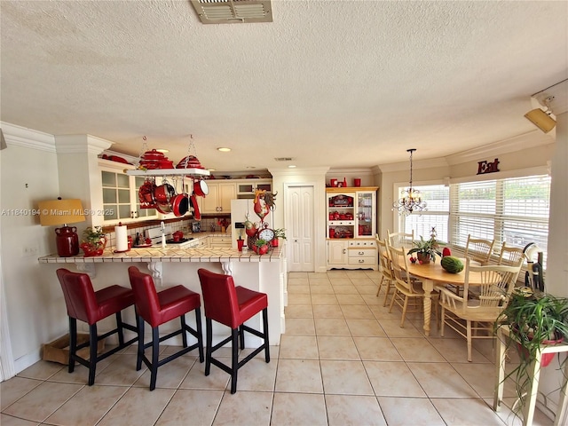 9057 SW 157th Path, Miami, FL 33196 - kitchen featuring freestanding refrigerator, ornamental molding, a peninsula, a kitchen bar, and a textured ceiling