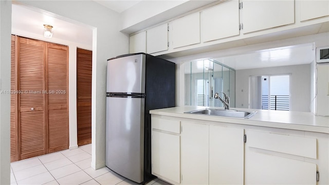 1033 Lenox Ave Unit 304, Miami Beach, FL 33139 - kitchen featuring freestanding refrigerator, light countertops, white cabinets, and light tile patterned floors