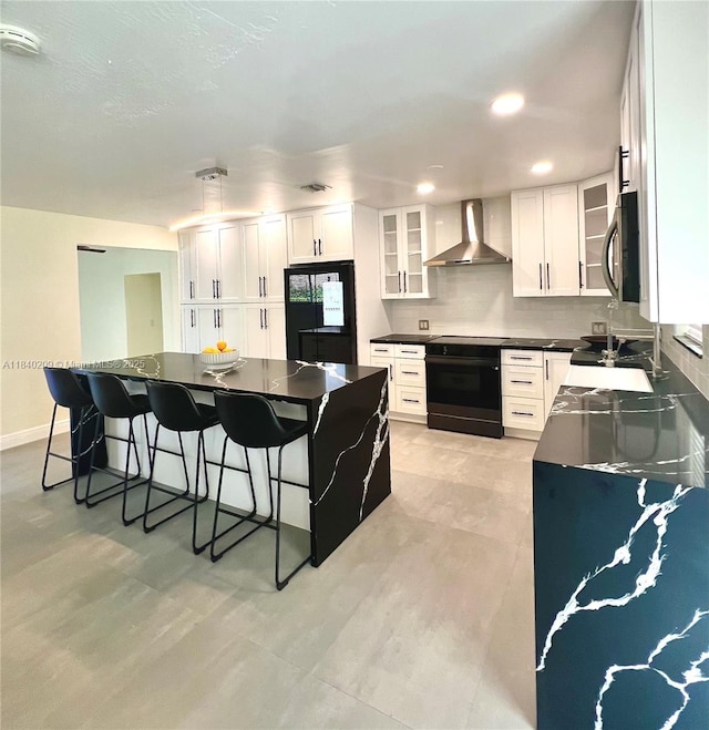 9130 SW 17th Ter, Miami, FL 33165 - kitchen with black / electric stove, wall chimney exhaust hood, refrigerator, dark countertops, and a breakfast bar