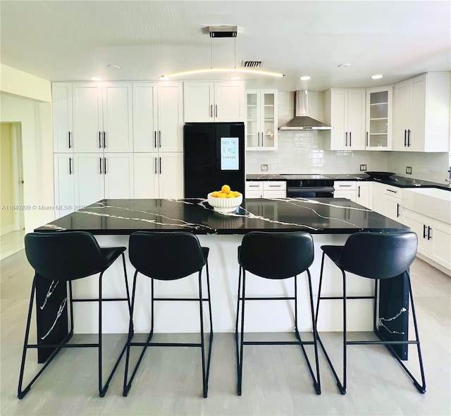 9130 SW 17th Ter, Miami, FL 33165 - kitchen featuring wall chimney range hood, freestanding refrigerator, white cabinets, backsplash, and a kitchen breakfast bar